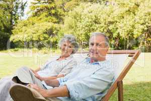 Happy mature couple sitting on sun loungers