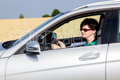 Woman driving car in front of the cereal field