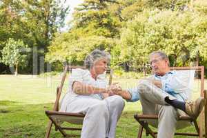 Relaxing mature couple sitting on sun loungers and talking