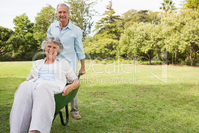 Happy man pushing his wife in a wheelbarrow