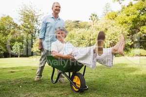 Happy man pushing his laughing wife in a wheelbarrow