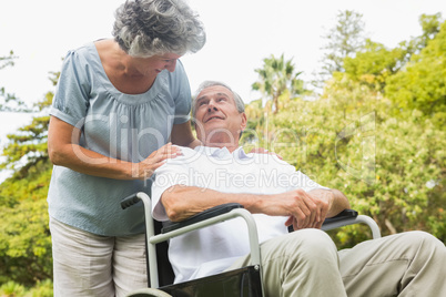 Cheerful mature man in wheelchair talking with partner