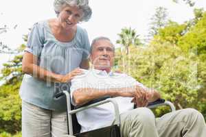 Cheerful mature man in wheelchair with his partner