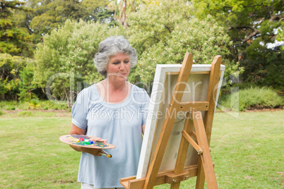 Happy mature woman painting on canvas