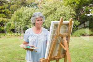 Happy mature woman painting on canvas