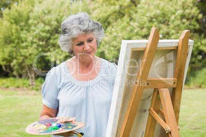 Content mature woman painting on canvas