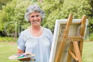 Happy mature woman painting on canvas