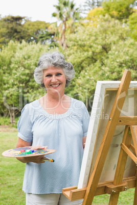 Smiling mature woman painting on canvas
