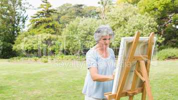 Peaceful retired woman painting on canvas
