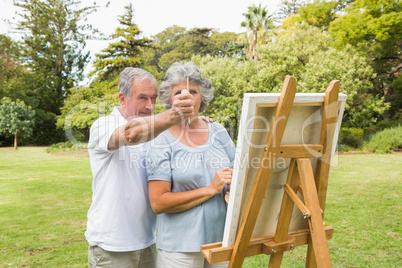 Content retired woman painting on canvas with husband