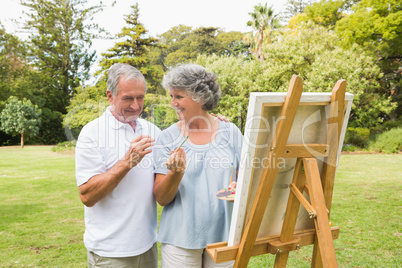 Smiling retired woman painting on canvas with husband