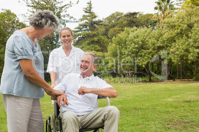 Happy man in a wheelchair laughing with his nurse and wife