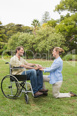 Happy man in wheelchair with partner kneeling beside him
