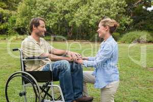 Smiling man in wheelchair with partner kneeling beside him