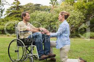 Content man in wheelchair with partner kneeling beside him