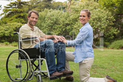 Handsome man in wheelchair with partner kneeling beside him