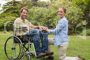 Handsome man in wheelchair with partner kneeling beside him
