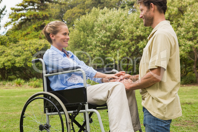 Attractive woman in wheelchair with partner kneeling beside her
