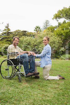 Attractive man in wheelchair with partner kneeling beside him