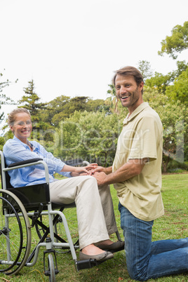 Blonde woman smiling in wheelchair with partner kneeling beside