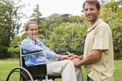 Happy woman in wheelchair with partner kneeling beside her