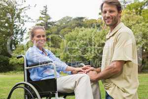 Happy woman in wheelchair with partner kneeling beside her