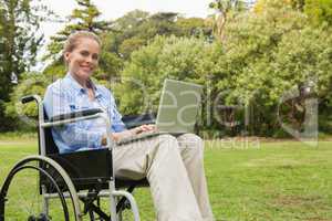 Smiling woman in a wheelchair with a laptop