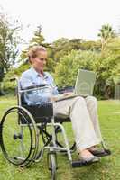 Happy woman in a wheelchair using a laptop