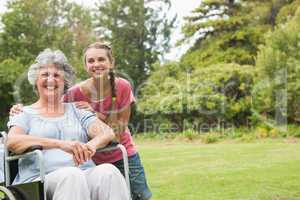 Grandmother in wheelchair and granddaughter smiling into the cam