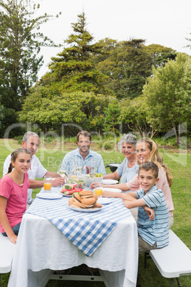 Multi generation family at picnic table having dinner outside