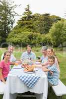 Multi generation family at picnic table having dinner outside