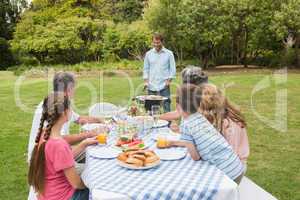 Cheerful extended family watching father at the barbecue