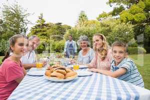 Smiling extended family waiting for barbecue being cooked by fat
