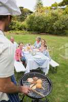 Happy extended family having a barbecue being cooked by father i