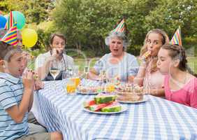 Family celebrating little girls birthday outside at picnic table