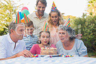 Happy extended family blowing out birthday candles together