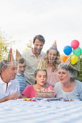 Cheerful extended family blowing out birthday candles together