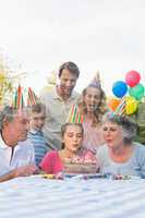 Cheerful extended family blowing out birthday candles together