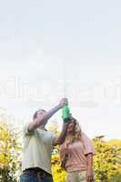 Man spraying bottle of champagne with blonde partner