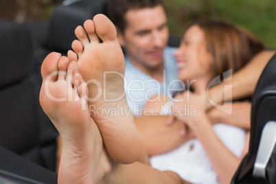Cute couple cuddling in the backseat with focus on foot