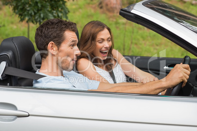 Laughing couple driving in a convertible