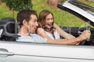Laughing couple driving in a convertible
