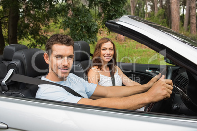 Happy couple driving in a silver convertible