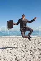 Cheerful businessman jumping on the beach