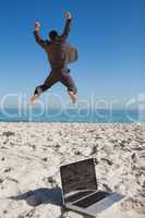 Victorious businessman in suit jumping leaving his laptop