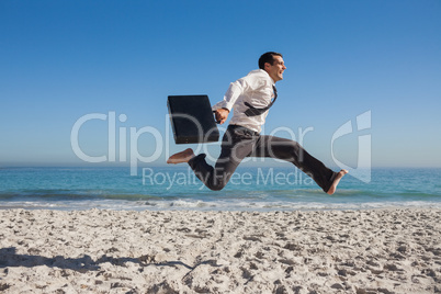 Cheerful businessman jumping on the beach