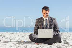 Young businessman with legs crossed typing on his laptop