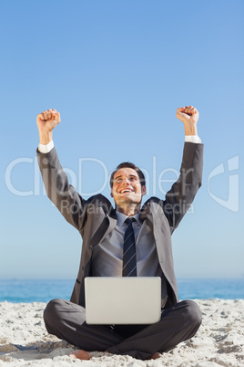 Victorious young businessman with his laptop
