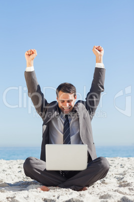 Victorious young businessman looking at his laptop