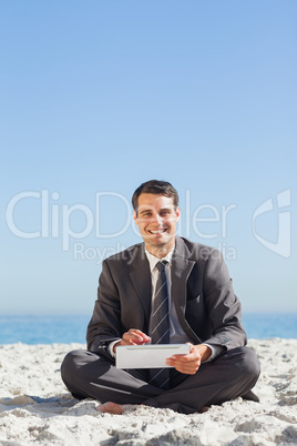 Smiling young businessman using his tablet computer
